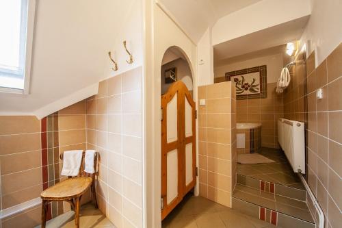 a bathroom with a shower with a wooden bench in it at Sziget Vendégház in Kőszeg
