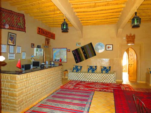 una sala de estar con una barra y un sofá en una habitación en Hôtel Riad Tadarte Familier, en Merzouga