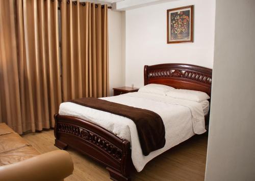 1 dormitorio con 1 cama grande y cortinas marrones en Hotel Cisne en Cuenca