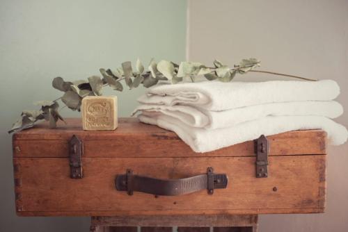 a pile of towels sitting on top of a wooden chest at Maison Hestiia Vexin 