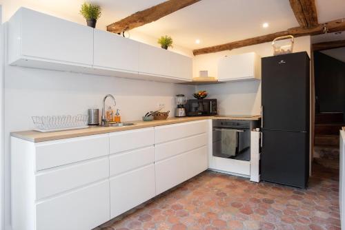 的住宿－Maison Hestiia Vexin，厨房配有白色橱柜和黑色冰箱。