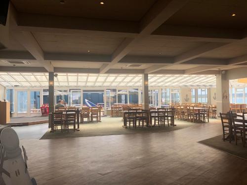 a large room with tables and chairs and windows at Cockleshell Chalet in Kidwelly