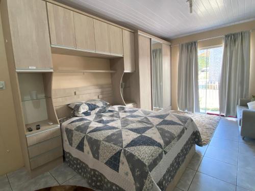 um quarto com uma cama e uma grande janela em Casa- Encanto da Praça em Urupema