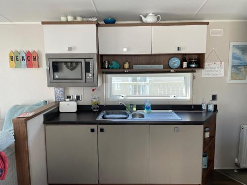 una pequeña cocina con fregadero y microondas en Ladram Bay Holiday Park D54 en Otterton