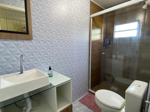 a bathroom with a sink and a toilet and a shower at Casa- Encanto da Praça in Urupema