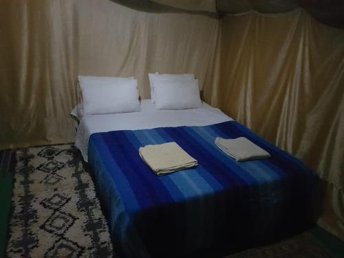 a bed in a tent with two towels on it at Merzouga Activities Camp in Merzouga