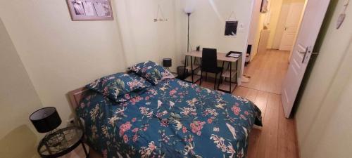 1 dormitorio con cama con edredón azul y escritorio en Appartement confortable avec parking gratuit sur place - Hypercentre de Nancy en Nancy