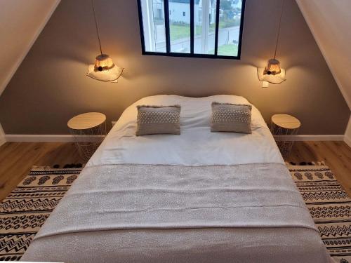 - une chambre avec un grand lit et 2 tables dans l'établissement LES PORTSALLAISES piscine ou spa à 300m de la plage, à Ploudalmézeau