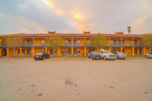 un grand bâtiment jaune avec des voitures garées dans un parking dans l'établissement OYO Hotel Kingsville - Hwy 77, à Kingsville
