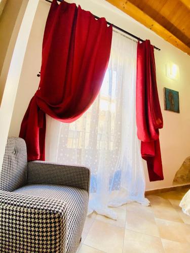 a window with red curtains next to a chair at Casa Calles in Siracusa