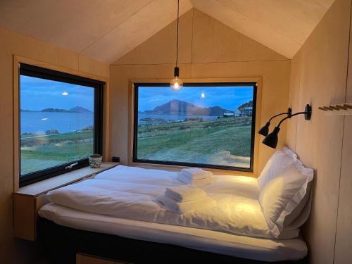 a bed in a room with two large windows at Kråen Gard in Larsnes