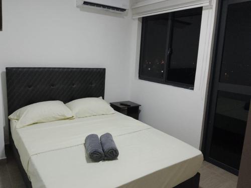 Un dormitorio con una cama con dos pares de zapatos. en HERMOSO Apartamento con piscina y cerca a PLAYA., en Santa Marta