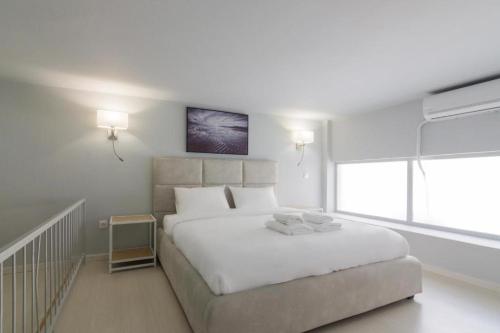 um quarto branco com uma cama grande e uma janela em Piraeus Urban Style Studio #2 em Piraeus
