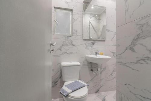 a white bathroom with a toilet and a sink at Piraeus Urban Style Studio #2 in Piraeus