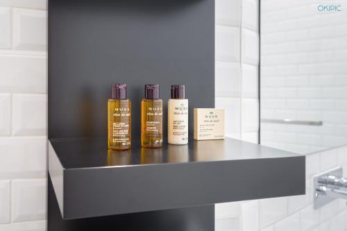 trois bouteilles d'huiles essentielles assises sur une étagère dans une salle de bains dans l'établissement Spacious 90sqm - Zen Latin District - Notre-Dame, à Paris