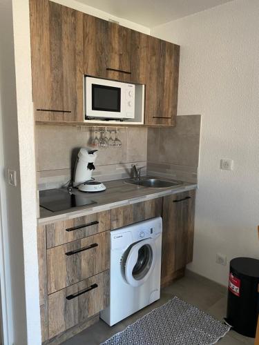 une cuisine avec un lave-linge et un micro-ondes dans l'établissement Le Phare, à Cogolin