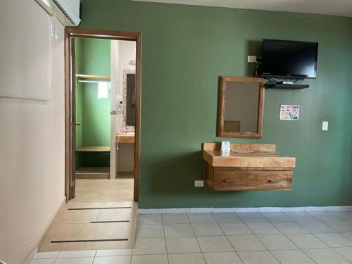 a room with a mirror and a television on a green wall at Hotel Santo Domingo Express in Villahermosa