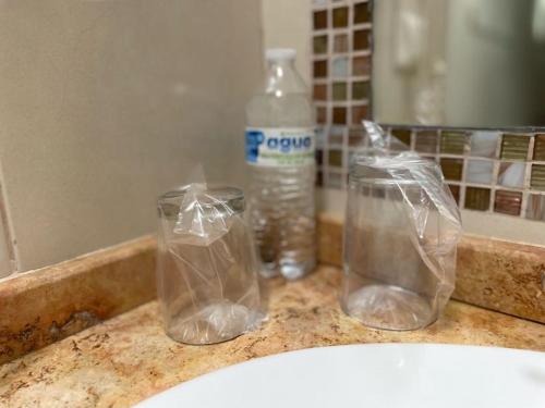 three plastic containers on a bathroom counter with a bottle of water at Hotel Santo Domingo Express in Villahermosa