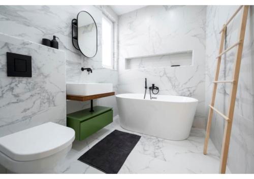een witte badkamer met een bad, een toilet en een wastafel bij Your Luxury Malta Home! in San Ġwann
