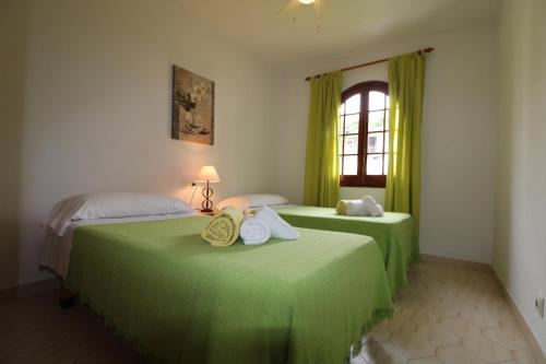 two green beds in a room with a window at Apartamento 2 habitaciones-wifi gratis in Son Bou