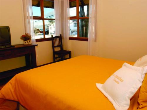 1 dormitorio con cama amarilla y TV en Cabañas Las Aguilas ADHERIDA PREVIAJE en Ushuaia
