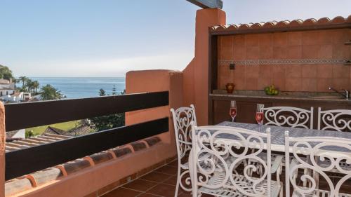 uma varanda com uma mesa e cadeiras e o oceano em ATICO DEL SOL - Playa Del Angel - Estepona em Estepona