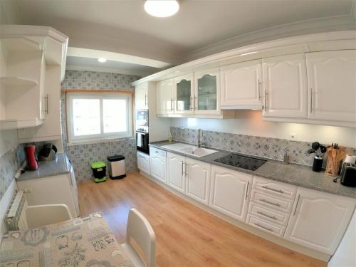 una cucina con mobili bianchi e pavimento in legno di Carnaxide modern T1 apartment w balcony in Carnaxide Oeiras Lisbon a Carnaxide