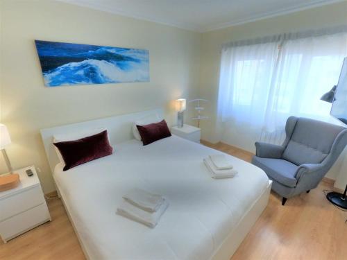 um quarto com uma grande cama branca e uma cadeira em Carnaxide modern T1 apartment w balcony in Carnaxide Oeiras Lisbon em Carnaxide