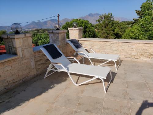 2 sillas blancas en la parte superior de un patio en Vasiliki Villa, en Orthés