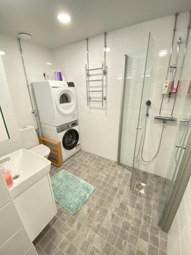 uma casa de banho com um chuveiro e uma máquina de lavar roupa em Family city apartment Helsinki em Helsinque