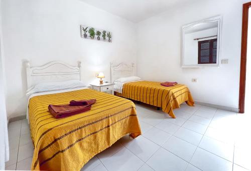 2 camas en una habitación blanca con sábanas amarillas en La Laguneta en Puerto del Carmen