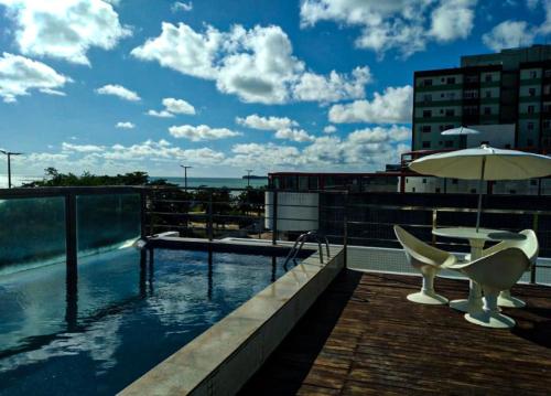 ein Balkon mit Tisch und Stühlen und einem Sonnenschirm in der Unterkunft Israel Flat Apt 122 in João Pessoa