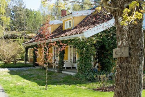 a yellow house with a sign on a tree at Engø Gård Hotel & Restaurant in Tjøme