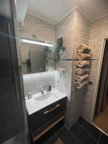 a bathroom with a sink and a mirror and towels at Myhomezen Chessy Disneyland Val d'Europe - 3D PlayStation 4 in Chessy