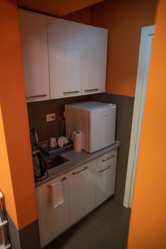 a small kitchen with white cabinets and a microwave at BOGO Apartment in Bitola