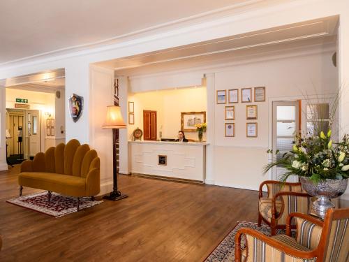 a living room with a yellow chair and a table at Grant Arms Hotel in Grantown on Spey