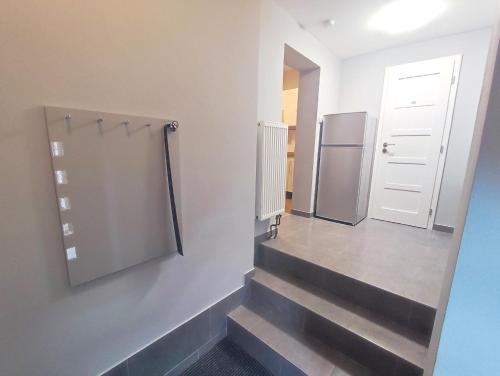 a hallway with stairs with a refrigerator and a door at Alisa Apartments in Kostomlaty