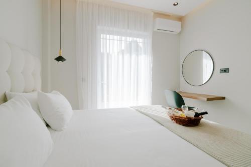 biała sypialnia z dużym białym łóżkiem i lustrem w obiekcie Aelia Prime Experience 3 w mieście Kos