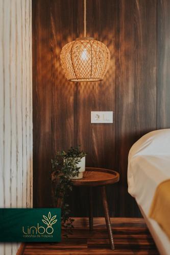 a room with a table and a bed and a lamp at Limbo Cabañas de Malpica in Malpica