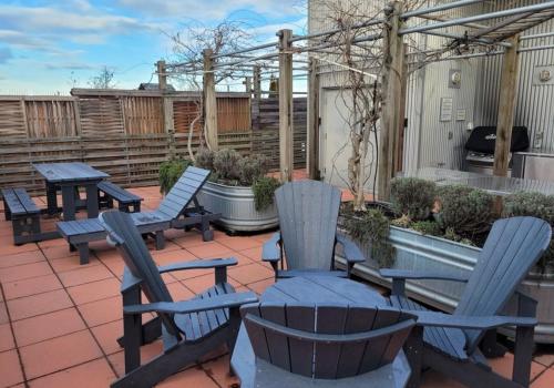 a patio with blue chairs and tables and a fence at Ocean Front Downtown Condo in Victoria