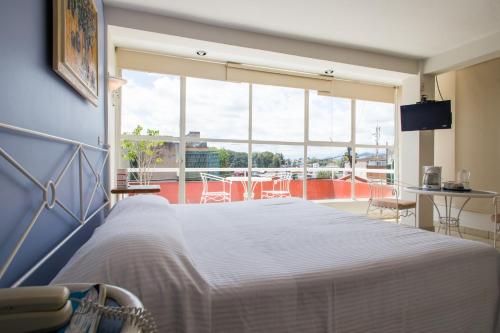 a bedroom with a white bed and a large window at Balcon del Alferez in Xalapa