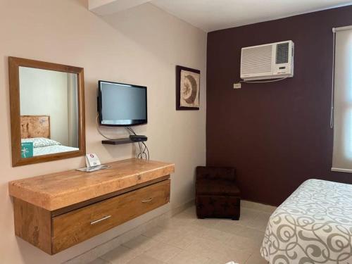 a bedroom with a dresser with a mirror and a television at Hotel Santo Domingo Express in Villahermosa