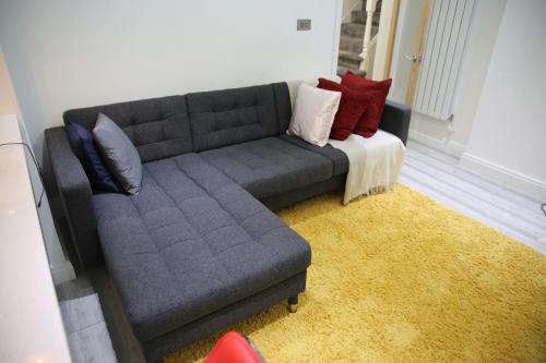 a living room with a gray couch with pillows at Rostron House in Manchester