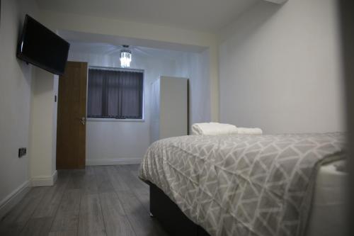 a bedroom with a bed and a flat screen tv at Rostron House in Manchester