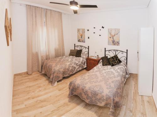 1 dormitorio con 2 camas y ventilador de techo en Tu Casa en Albacete, en Albacete