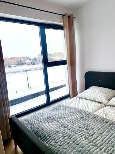a bedroom with a bed and a large window at Apartament Nowomiejska in Suwałki