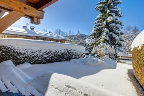 a snow covered yard with a house and a tree at Charming flat with garden nearby the slopes - Welkeys in Megève