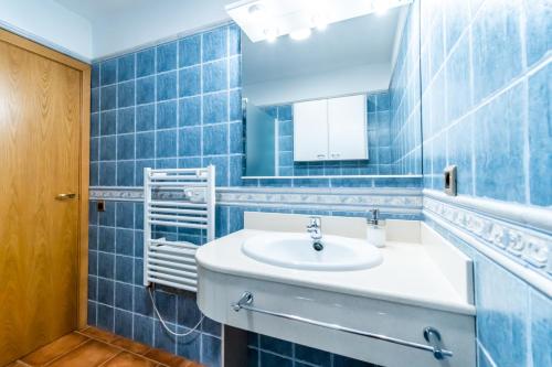ein blau gefliestes Bad mit einem Waschbecken und einem Spiegel in der Unterkunft CASA TERE in Valderrobres