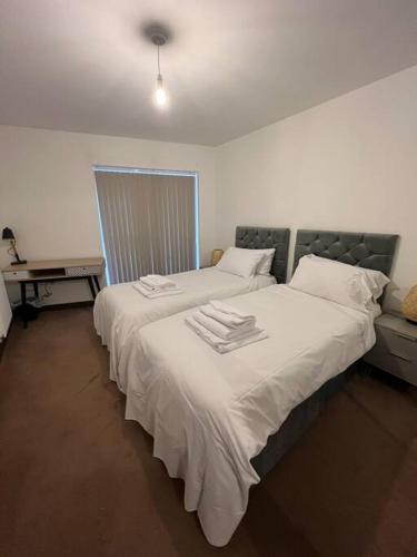 a bedroom with a large white bed with towels on it at Dartford Lux Stay 1 bedroom apartment- free parking next to station in Dartford