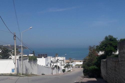 an empty street with a white building and the ocean at *APPARTEMENT NEUF AVEC TERRASSE À LA MARSA*** in La Marsa